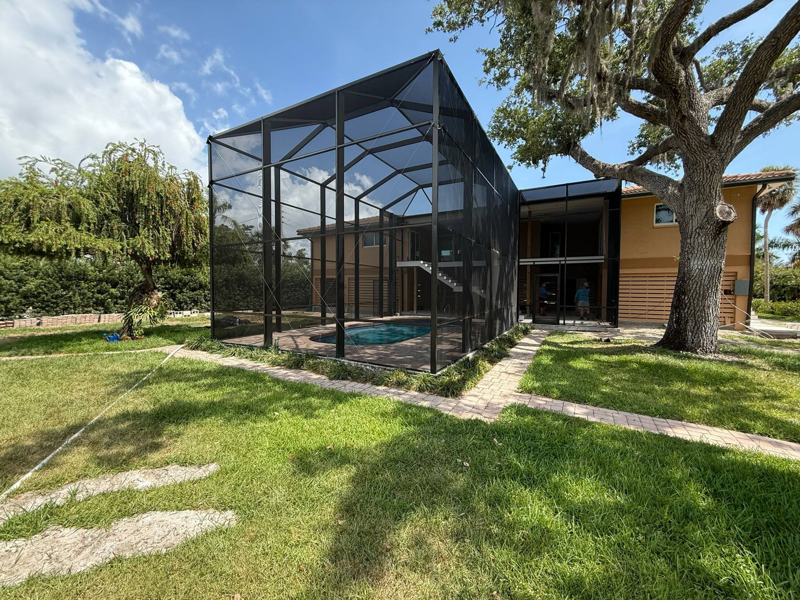 Black aluminum screen room installation enclosing pool area in Lakeland, FL